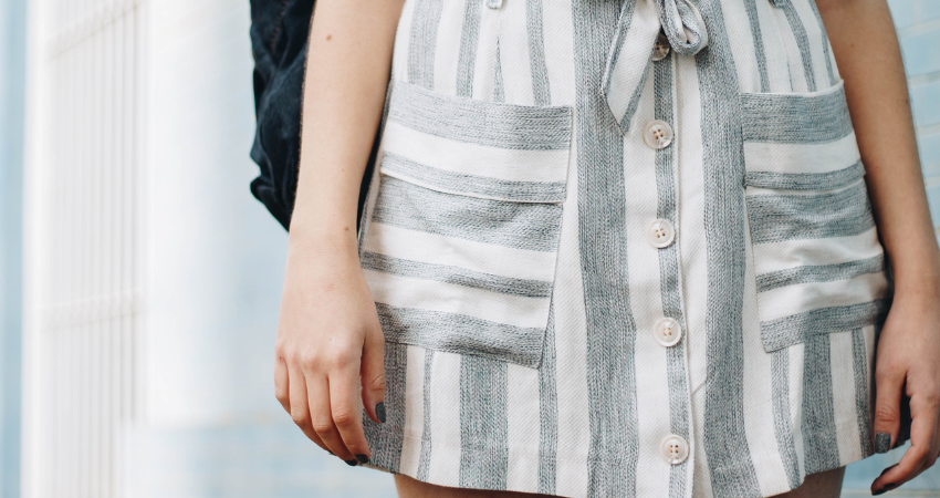 A close up of a white and grey striped skirt with large pockets.